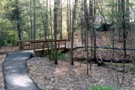 The trail crosses a bridge and ends at an intersecting trail.