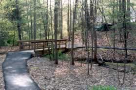 The trail crosses a bridge and ends at an intersecting trail.