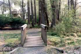 A gravel path intersects after crossing the bridge.  Continue straight on the present path.