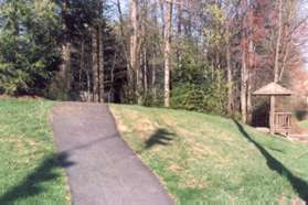 Turn right and follow the asphalt path into the woods on the other side.