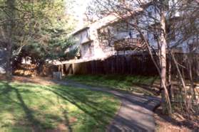 The path appears to go straight into the townhouse area.  Turn right to continue in the woods.