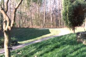 At the end of the straight section of concrete sidewalk turn right to follow the gravel path between the houses.