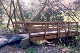 The trail appears to end at an intersecting trail. Cross the bridge to the right and turn left to continue along the other side of the stream.