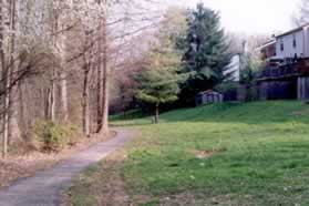 After crossing the bridge turn left to continue following the stream. Houses should be on your right.