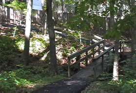 The path crosses another bridge and turns left to head up a hill between fences.
