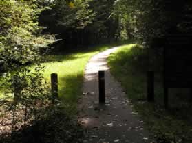 The asphalt trail passes through a vehicle barrier.