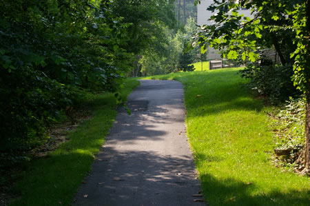 The trail enters the woods behind the homes on the right.