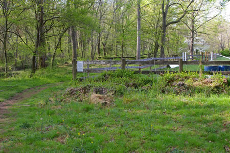 The trail leaves the woods and passes a fenced area for horses.
