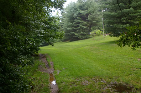 The trail enters a grassy area. Hunter Village Dr. can be seen on the right.