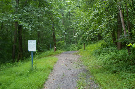 The trail crosses a water main. The trail surface changes to asphalt.