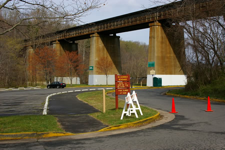 Follow the asphalt trail on the side of the parking lot and go under the railroad bridge.