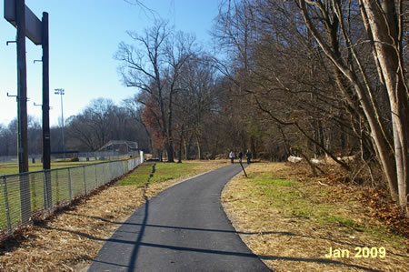 The trail passes next to a fence for the baseball field.