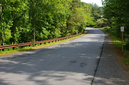Turn right and follow the gravel shoulder of the road next to the guardrail.