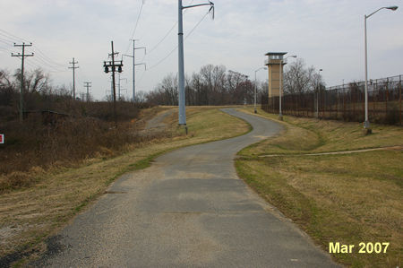 Follow the asphalt road with the  prison fence on your right.