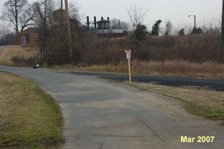 The access road is intersected by an asphalt trail from the right. Turn sharply right to follow that trail and end the detour.