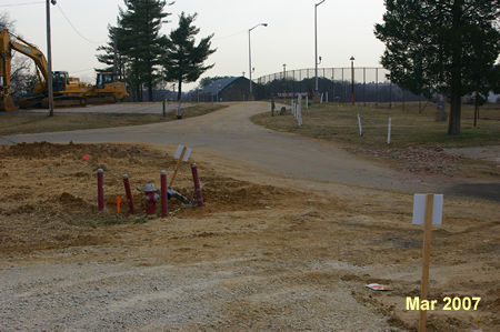The gravel trail connects to the access road around the prison. Continue straight on the access road with the prison fence on your right.