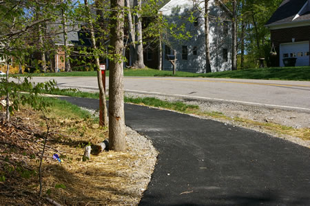 The asphalt trail merges into a concrete sidewalk along Creekside View La.