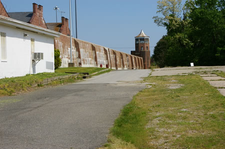 Follow the perimeter road along the wall of the prison.
