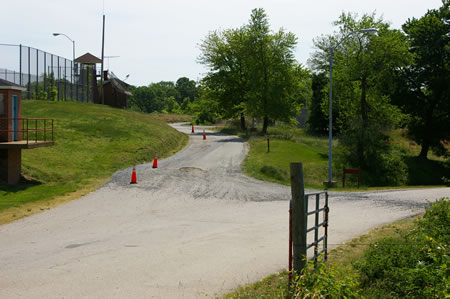 Keep to the left at the intersecting road. The perimeter road follows the prison fence.