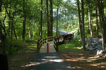 The trail crosses a bridge and goes up a curved ramp to climb the hill.