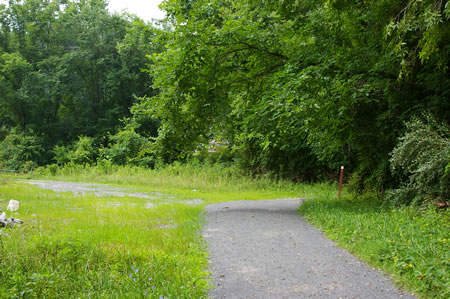 The trail turns to the right at a connection to a maintenance building on the left.