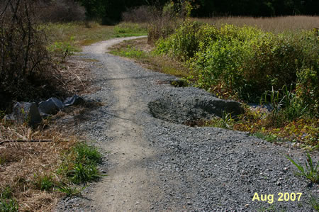 The trail crosses a pipe and drainage ditch. Storms have washed out part of the trail here.