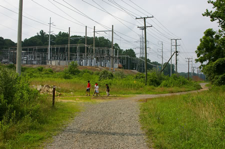 A bicycle trail intersects from the left. Continue straight on the present trail to pass the power station.