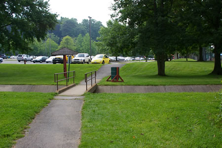 The trail joins an asphalt trail from the tennis courts and crosses a bridge over a drainage ditch.