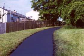 The path goes up the hill behind the homes.