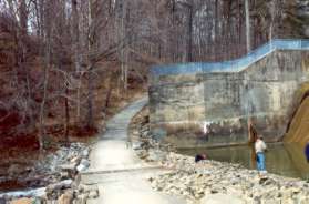 The asphalt trail goes up a steep hill next to the dam.
