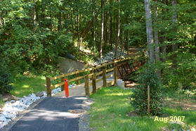 The trail crosses a stream on a bridge at the bottom of the hill.