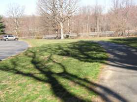 The trail passes over a hill with a parking area to the left.