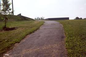 The trail climbs a grassy hill.