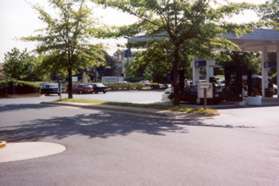 Cross the entrance road to the sidewalk in front of the service station.