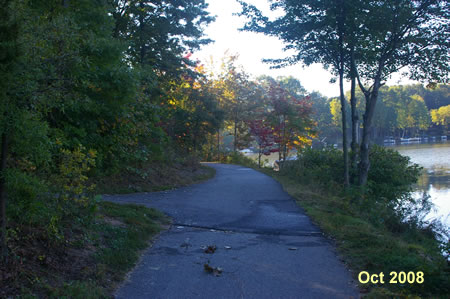 An asphalt trail intersects from the left. Continue straight on the present trail.