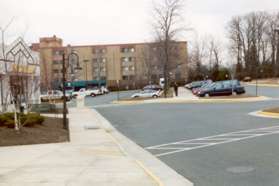 At the end of the stores cross to the sidewalk leading to the large building at the end of the parking lot.