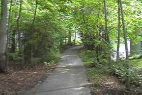 The path turns right and passes between homes on both sides.