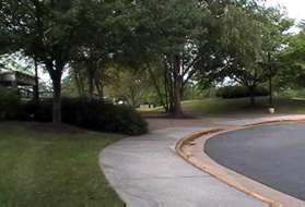 Turn left to follow the sidewalk along the access road to the pool parking lot.