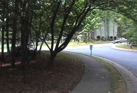 Turn right to follow the sidewalk along the street after passing the houses.