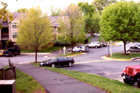 The paths turns slightly to the right after crossing a parking area.