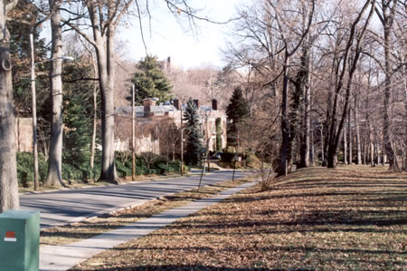 Take the sidewalk to the left along the street directly across Mass. Ave. from Lovers Lane.  The sidewalk shown on the right ends at the next curve in the road. This is Rock Creek Dr.