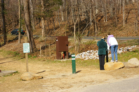 Visitors are shown examining a map next to the parking lot.