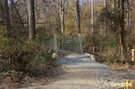 The trail crosses a short bridge over a ditch.