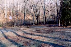 The path turns left at a trail intersection near a  basketball court.