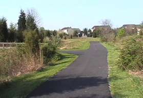 An asphalt trail intersects from the left.  Continue straight on the present trail.