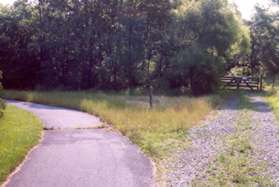 A gated trail diverges to the right. Continue on the paved trail to the left.