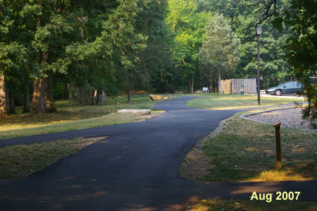 The trail crosses 2 asphalt trails leading to a parking lot on the right.