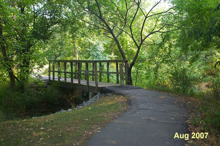 The trail crosses a narrow bridge over a side stream.