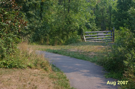 After crossing the bridge notice the gate to a natural surface trail on the right.  Continue straight on the asphalt trail to the left.