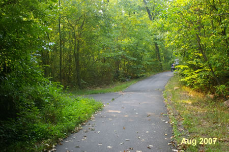 An asphalt trail intersects from the left.  Continue straight on the present trail.